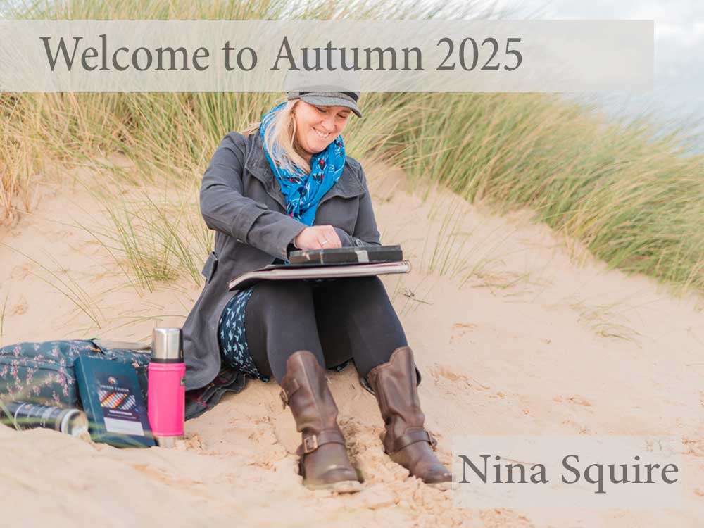 Nina Squire sitting on sand dunes, smiling, with art supplies, promoting pastel art workshop.