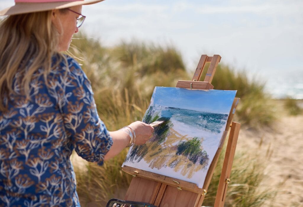 Nina Squire creating a landscape painting outdoors on a beach for her online and in person soft pastel workshops