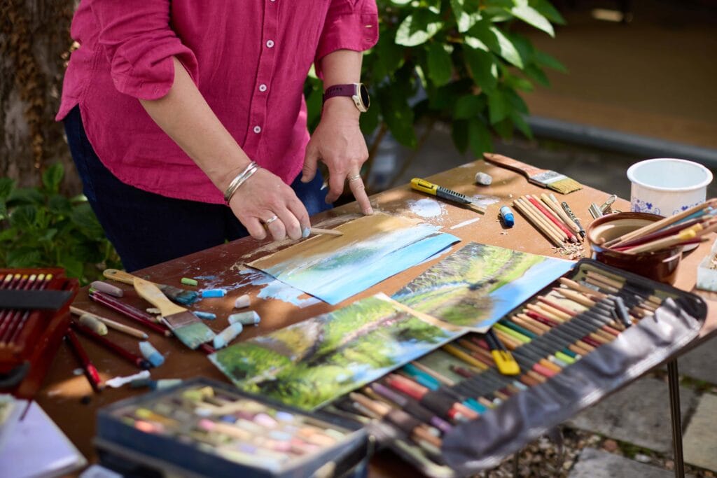Artist Nina Squire creating landscape art with pastels outdoors.