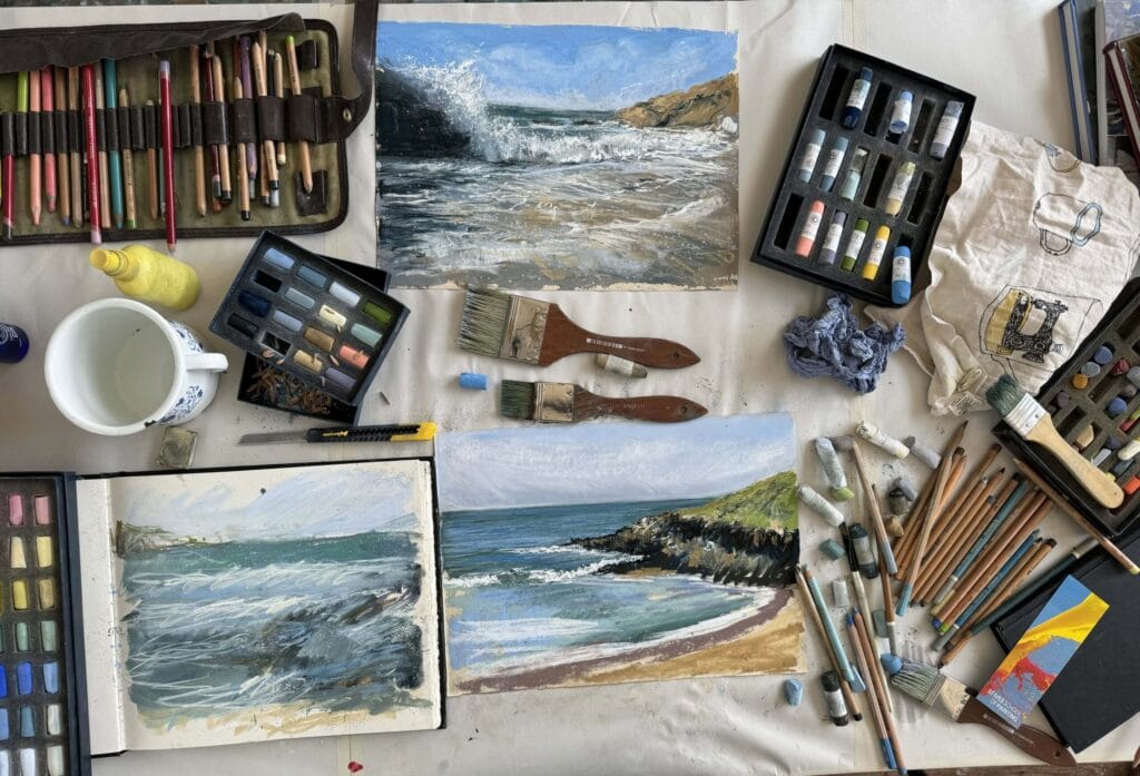 Artist Nina Squire's workspace with seascape and beach paintings and art supplies.