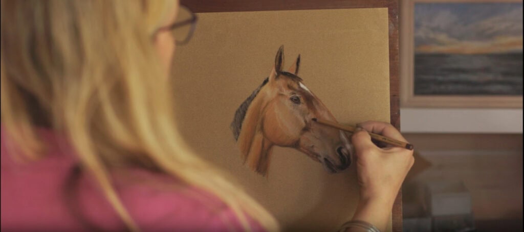 Artist Nina Squire completing one of her pet portrait commissions, painting a realistic horse portrait in soft pastel.