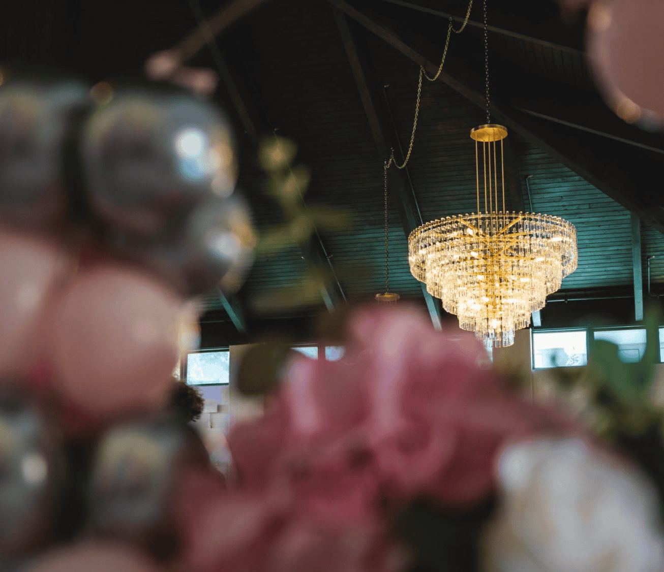 View of a chandelier with flowers and balloons blurred in front