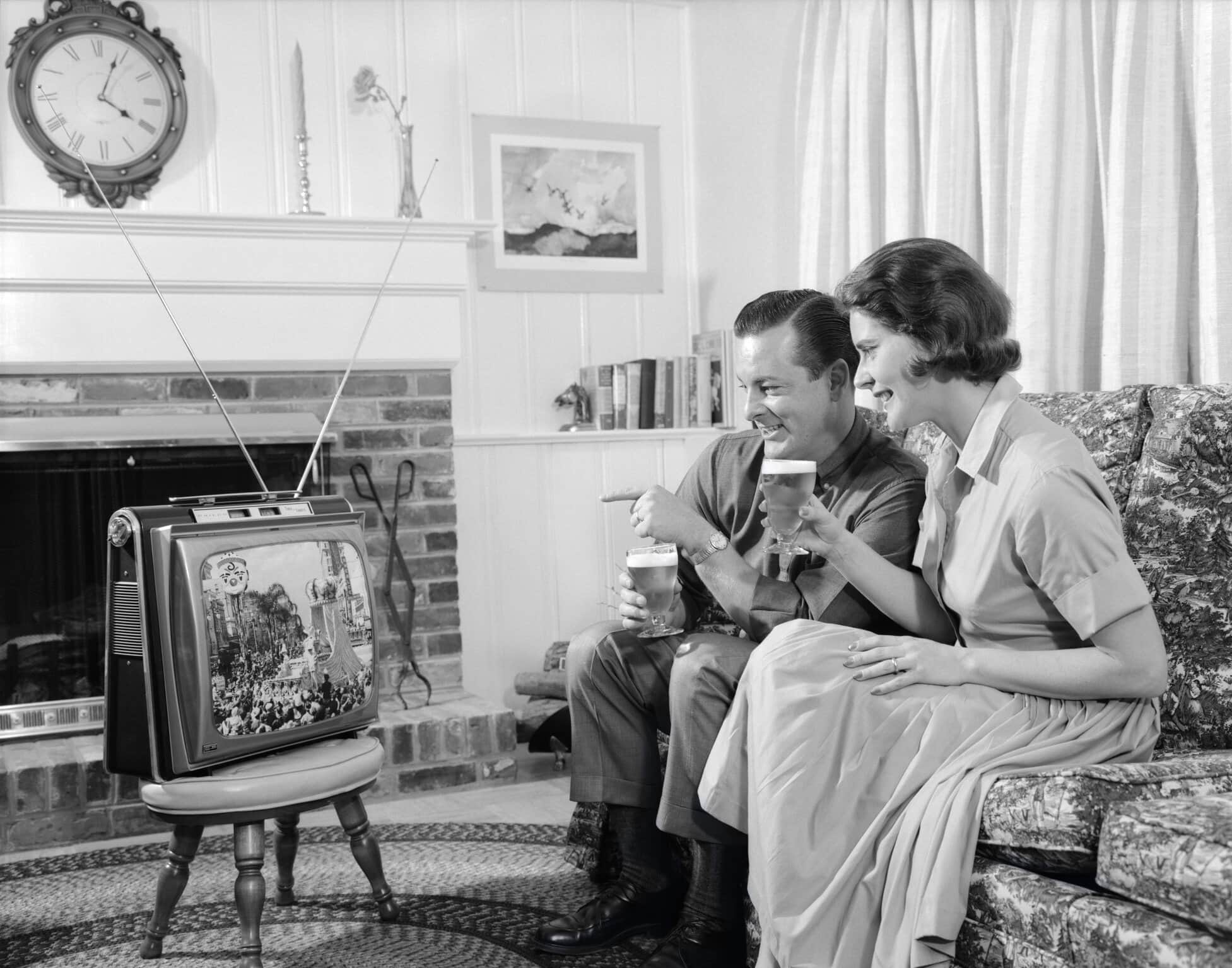 A couple watching tv in black and white.
