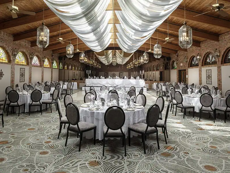 View of the ballroom with tables and chairs, and drapes hanging from the wooden ceiling beams.