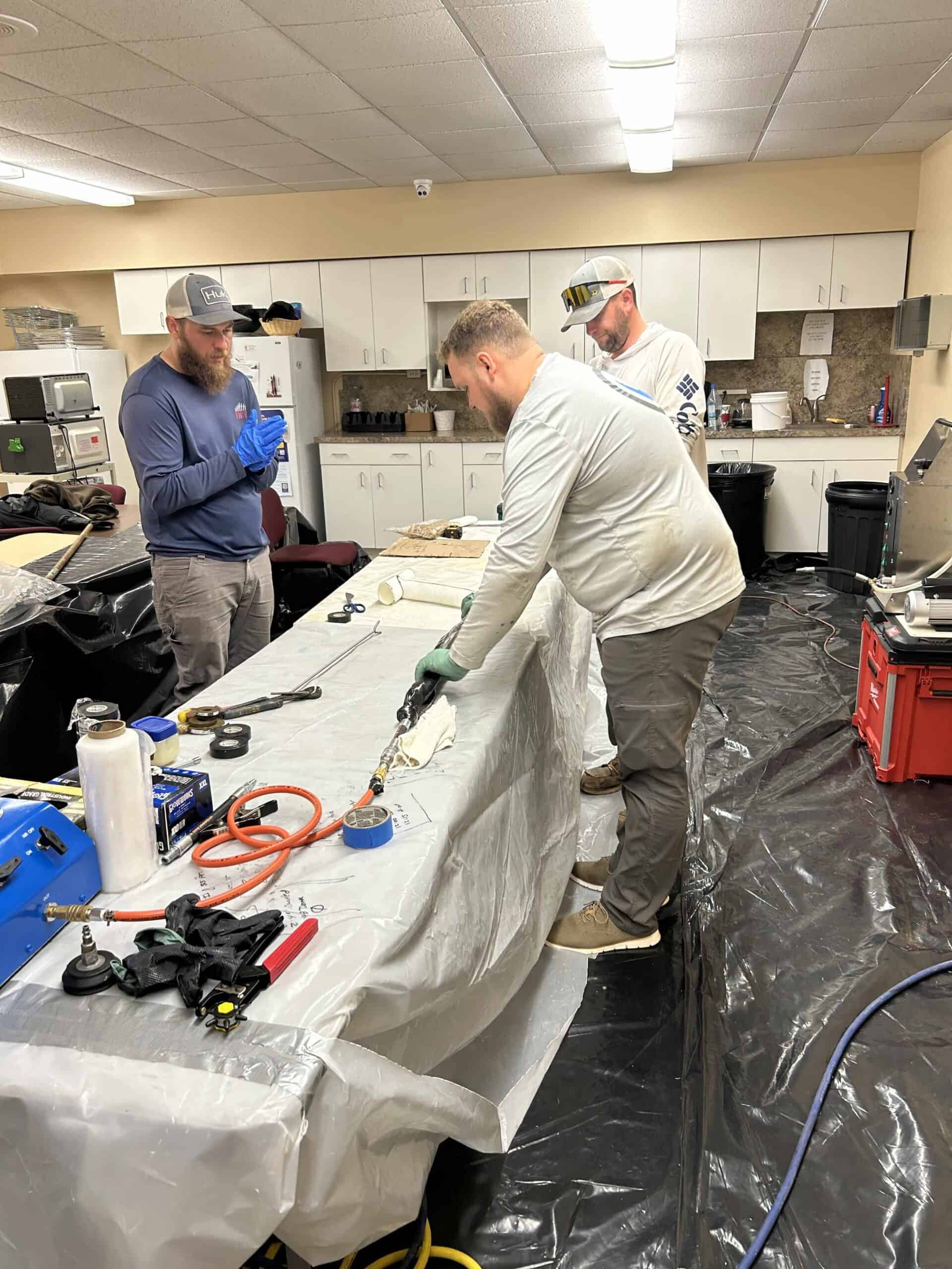 Technicians repairing water leak with advanced tools in a commercial kitchen.