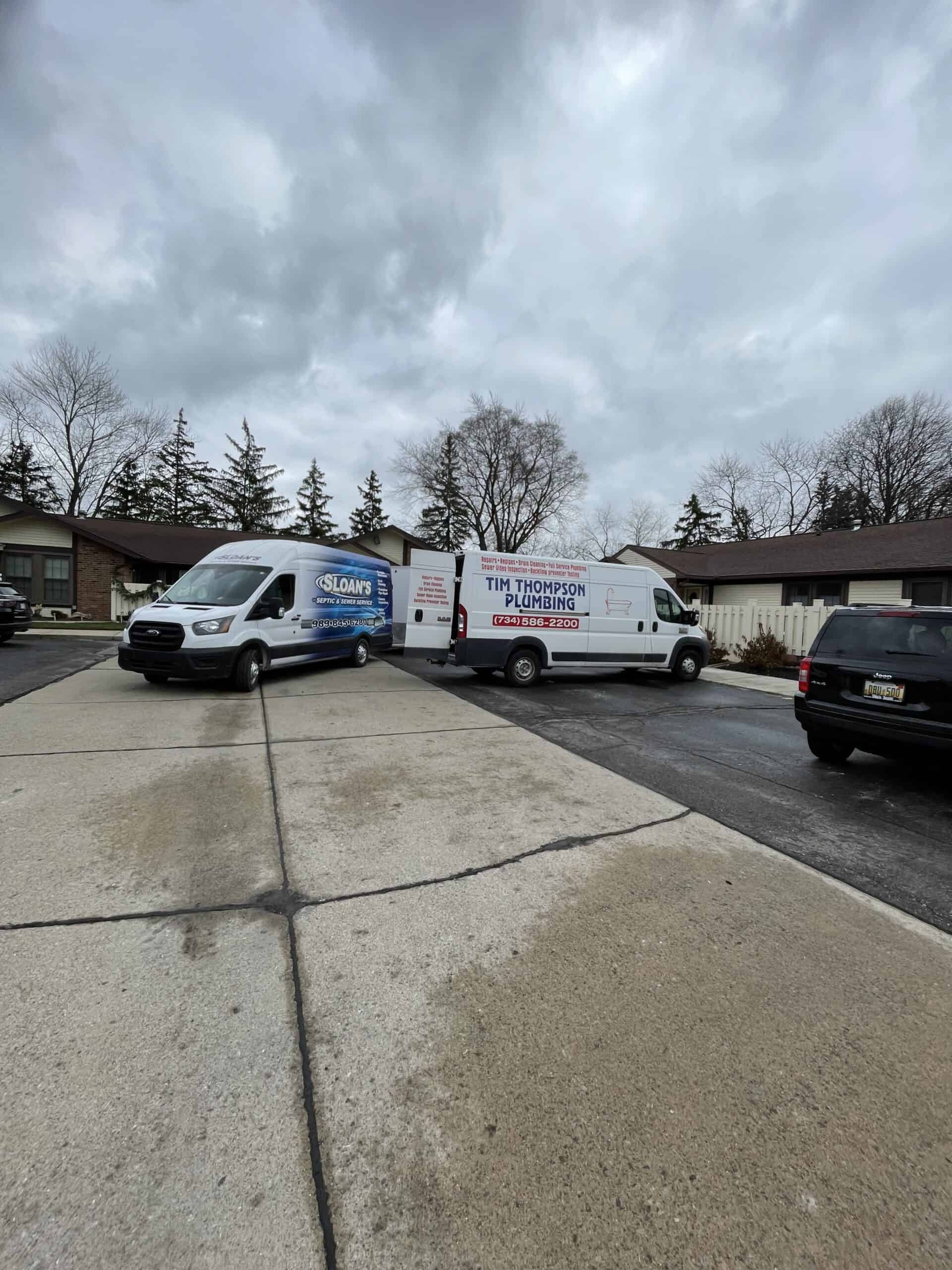 Trenchless plumbing and hydro jetting trucks parked in a residential driveway.