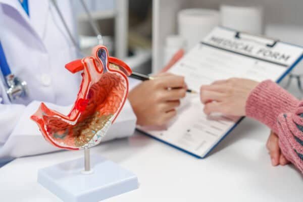 female medical professional a stethoscope is holding a clipboard, possibly discussing gastritis