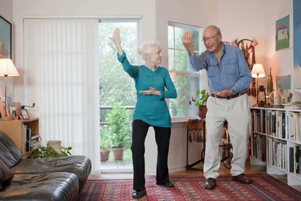 Senior couple enjoying a playful moment dancing in their cozy living room.