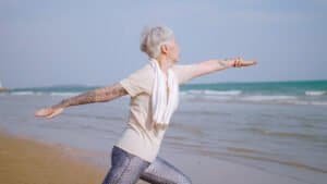 Asian elderly woman exercising on the beach. Retired woman stretching before jogging.