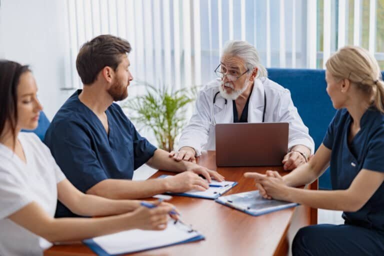 Group of doctors sitting at meeting table in conference room during seminar. High quality photo