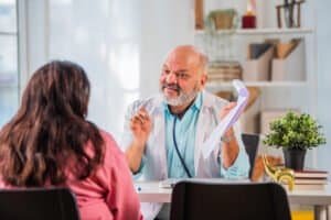 Indian asian senior elderly old Doctor discussing case with female patient in cliunic