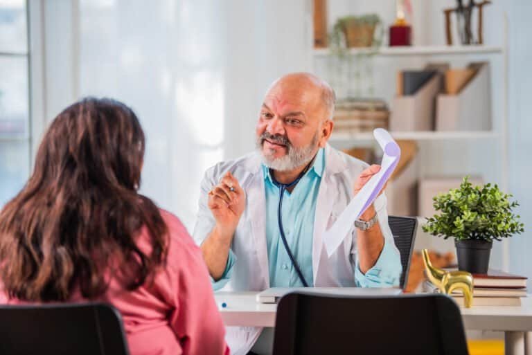 Indian asian senior elderly old Doctor discussing case with female patient in cliunic