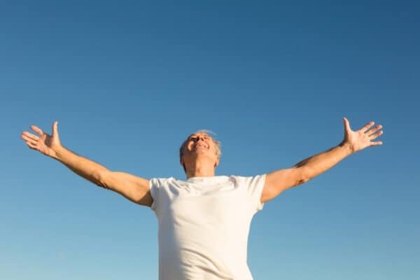 Low angle view of man with arms outstretched standing against clear sky