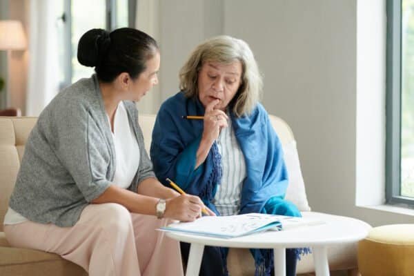 Nursing home patients solving crossword puzzle in lounge area