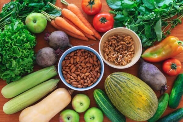 Organic fresh vegetables, almonds and walnuts. Vegan healthy raw food on wooden table background. Top view, flat lay.