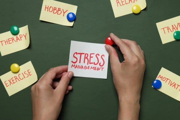Papers with words and hands on dark green background, top view
