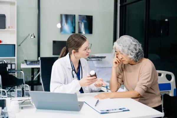 Portrait of female doctor explaining diagnosis to her patient. Doctor Meeting With Patient In Exam Room. A medical practitioner reassuring a patient in hospital