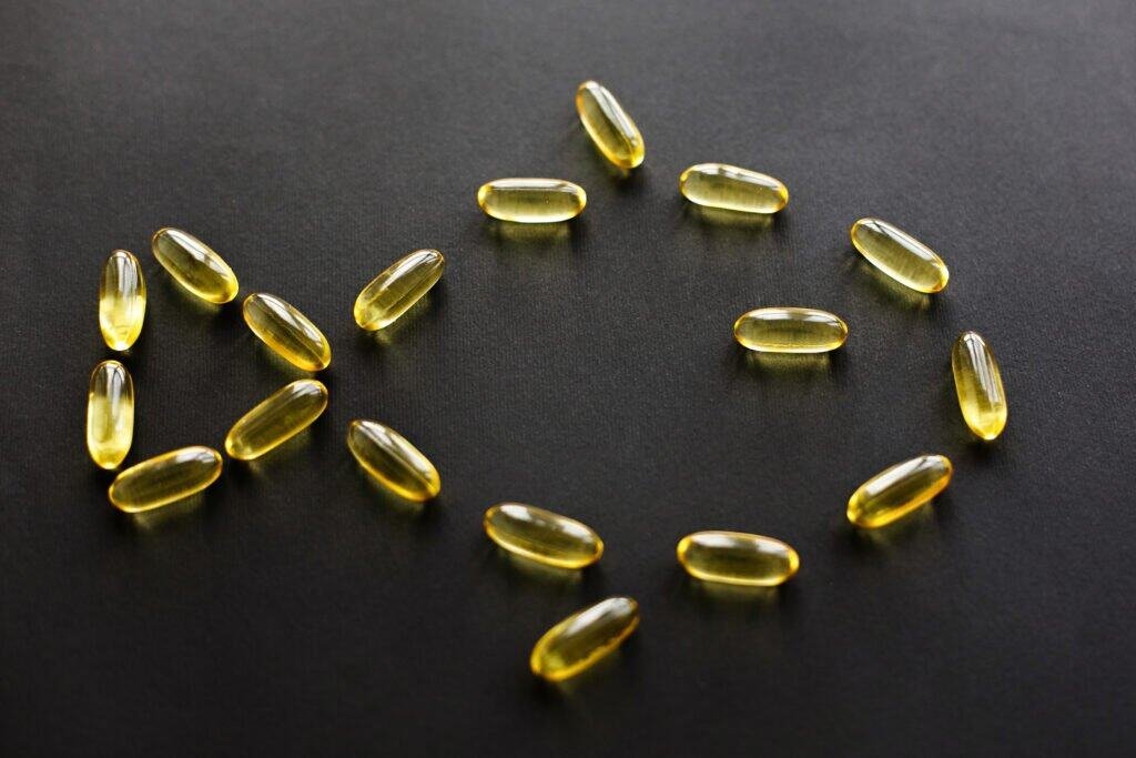 Omega 3 concept. Omega capsules in fish shape on black dark background. Fish oil pills. Dietary supplements. Health support and treatment. Biologically active additives.