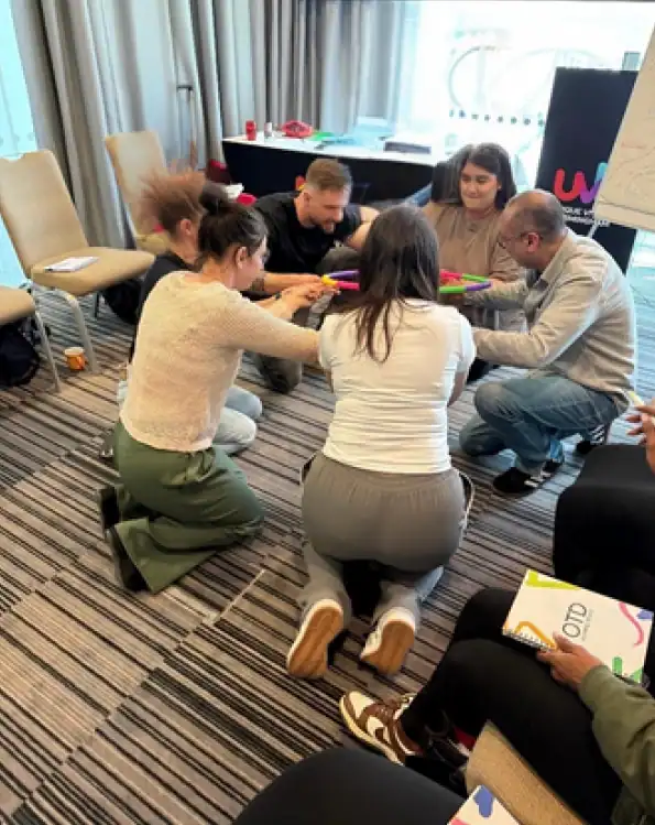 Team-building exercise with colorful rods indoors.