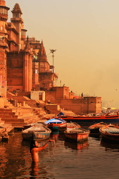 Indian man bathing and making offerings at the Ganges River in Varanasi, Uttar Pradesh, India