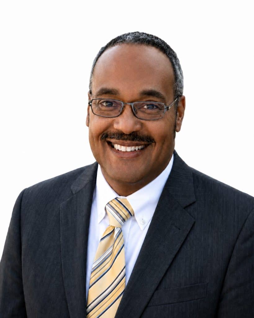 Smiling businessman in suit and tie with glasses for professional profile.