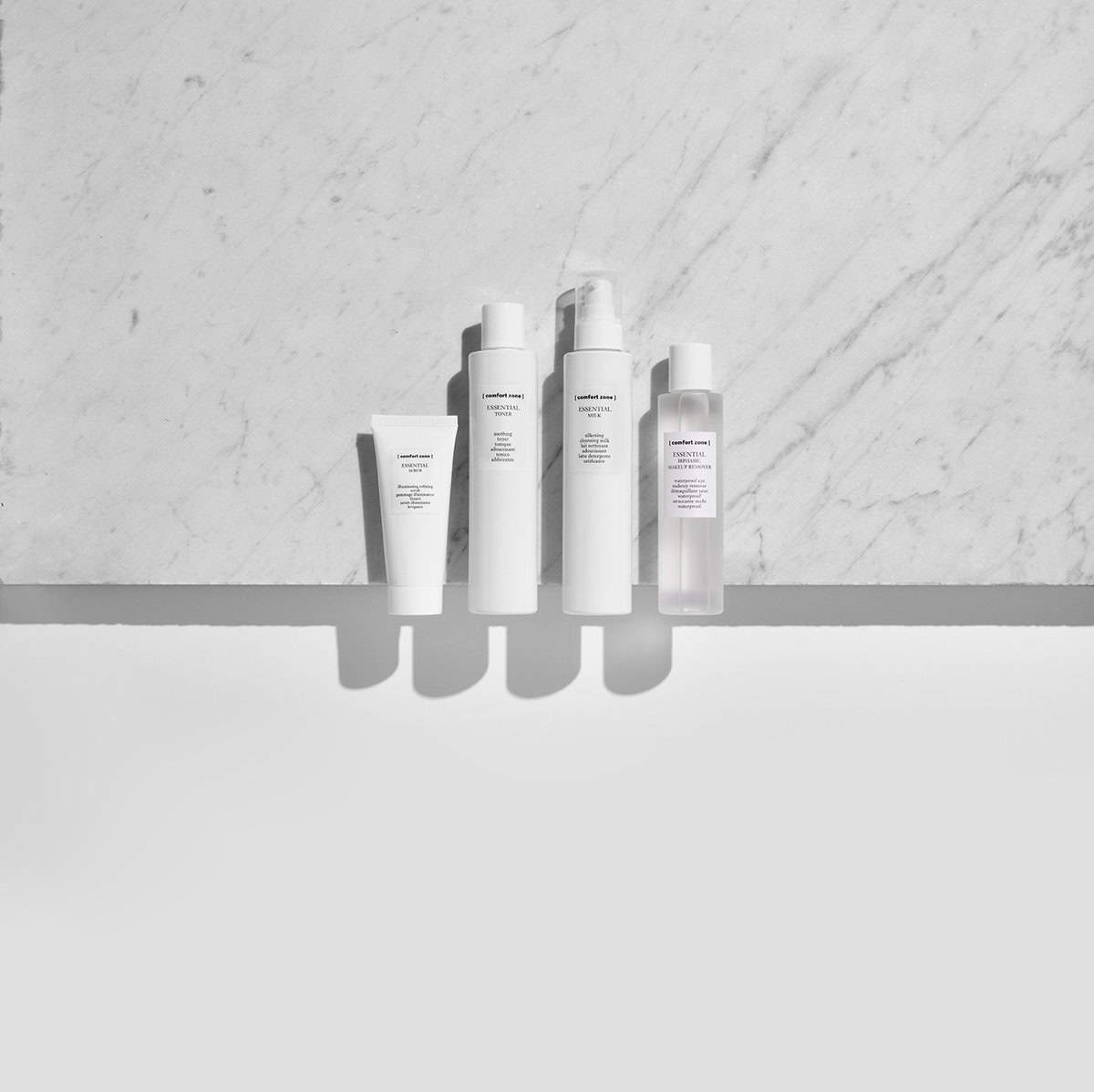 Minimalist skincare bottles for facial cleansing on marble background.