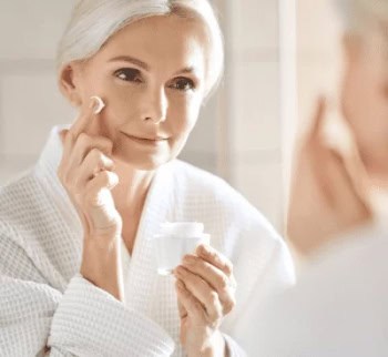Woman applying skincare cream, skincare routine, mature woman, beauty treatment.