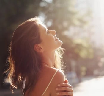 Beautiful woman enjoying sunshine with glowing skin for a holiday glow.