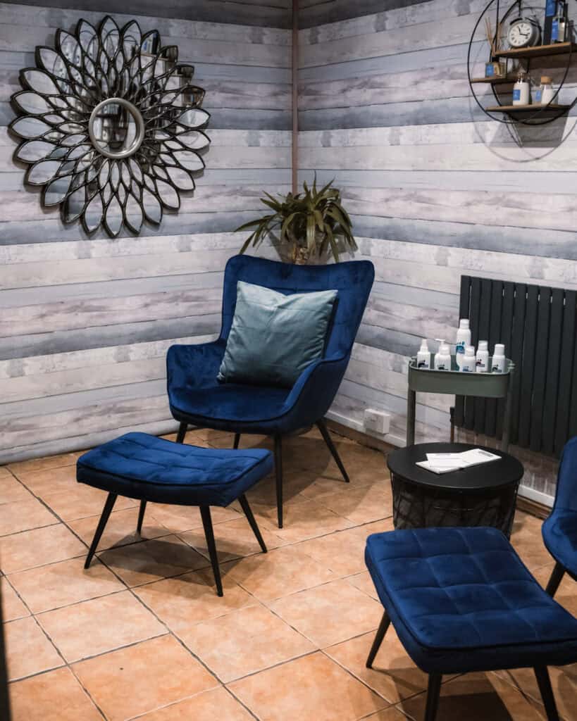 Relaxing spa room with comfortable blue chairs and soothing decor for waxing services.