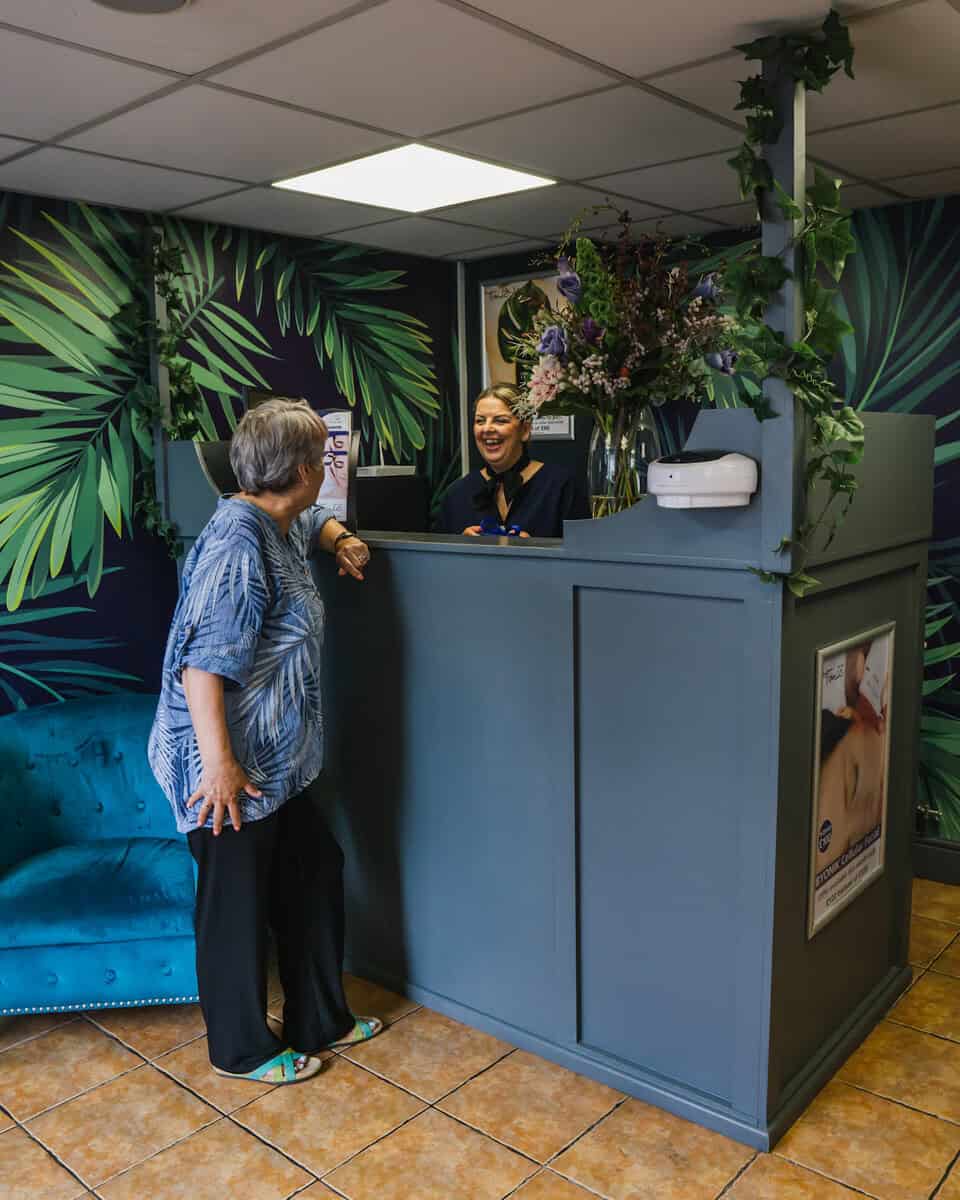 Friendly receptionist assisting a guest at Tonic Day Spa reception.