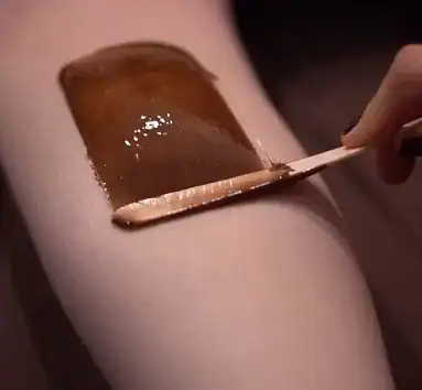 Close-up of waxing process on leg at Tonic Day Spa, professional hair removal service.