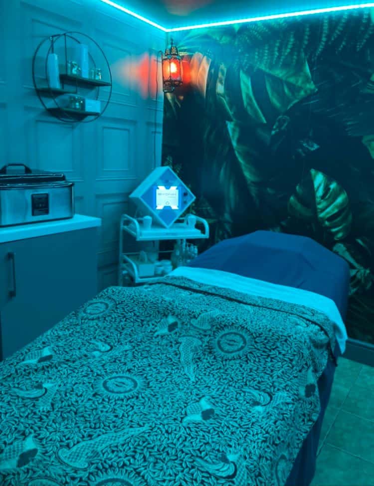 Cozy massage bed in a tranquil spa room with ambient lighting and tropical wall decor.