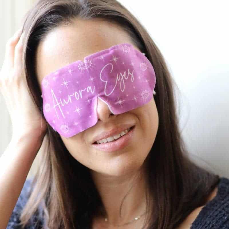 Woman wearing pink Aurora Eye Mask for relaxation and eye care.