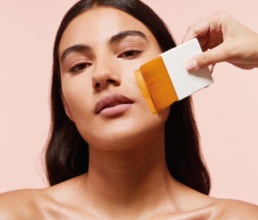 Woman receiving a facial treatment with a brush at Tonic Day Spa.