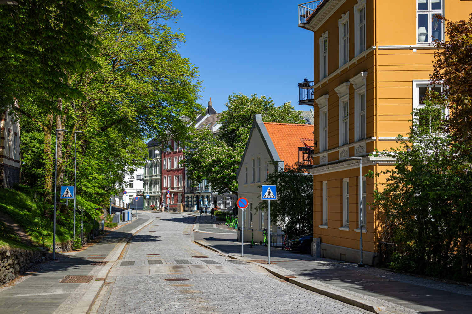 Colorful European street with vibrant buildings and lush greenery, perfect for exploring scenic fjord destinations.