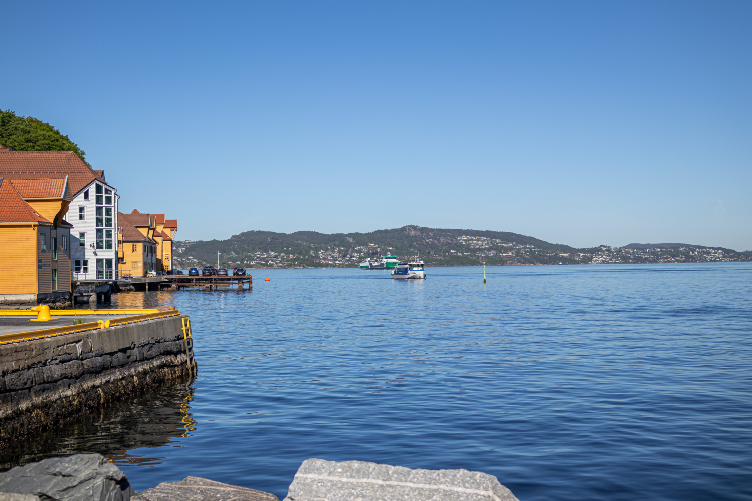 Colorful Norwegian harbor with traditional wooden houses and boats on the fjord.
