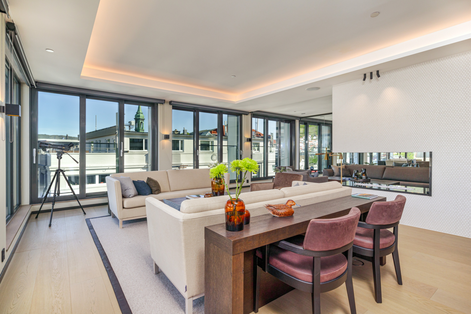 Luxurious modern living room with large windows overlooking cityscape and a telescope for city viewing.