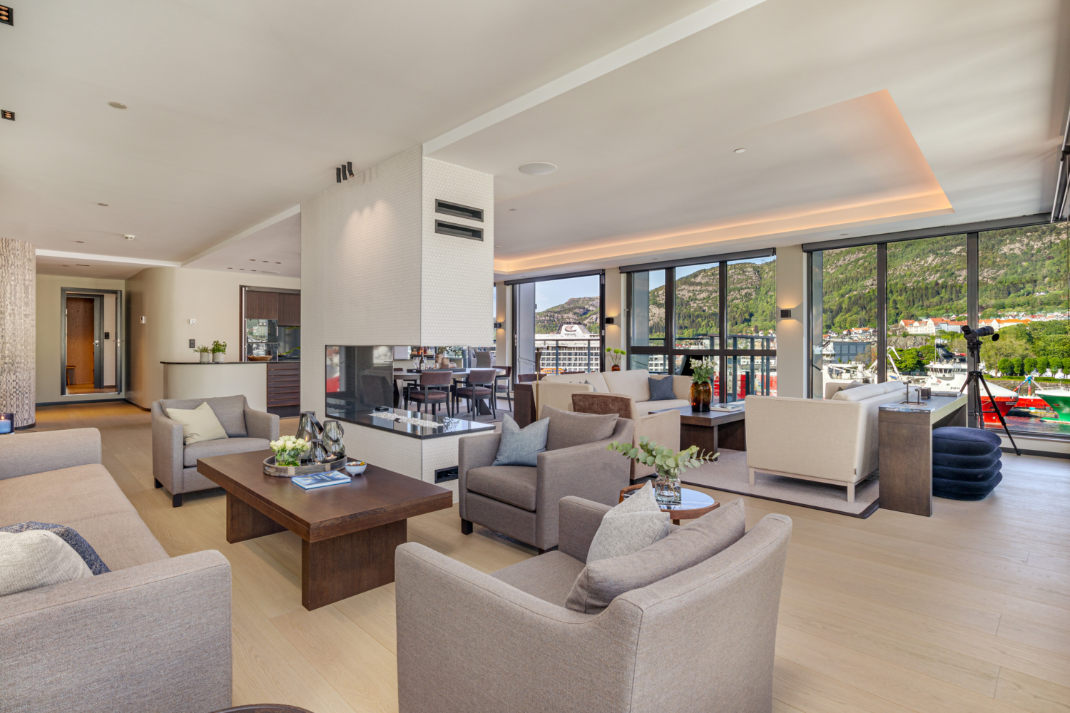 Luxurious fjord view living room with modern decor and large windows overlooking mountains and boats.