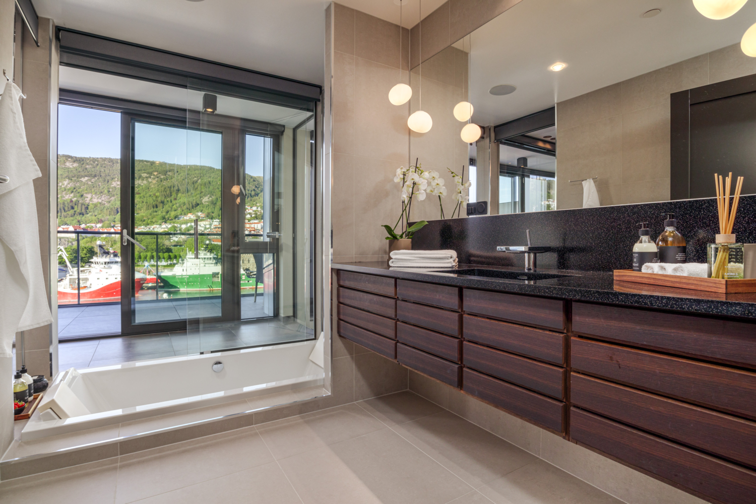 Luxurious modern bathroom with a scenic fjord view through floor-to-ceiling glass door.