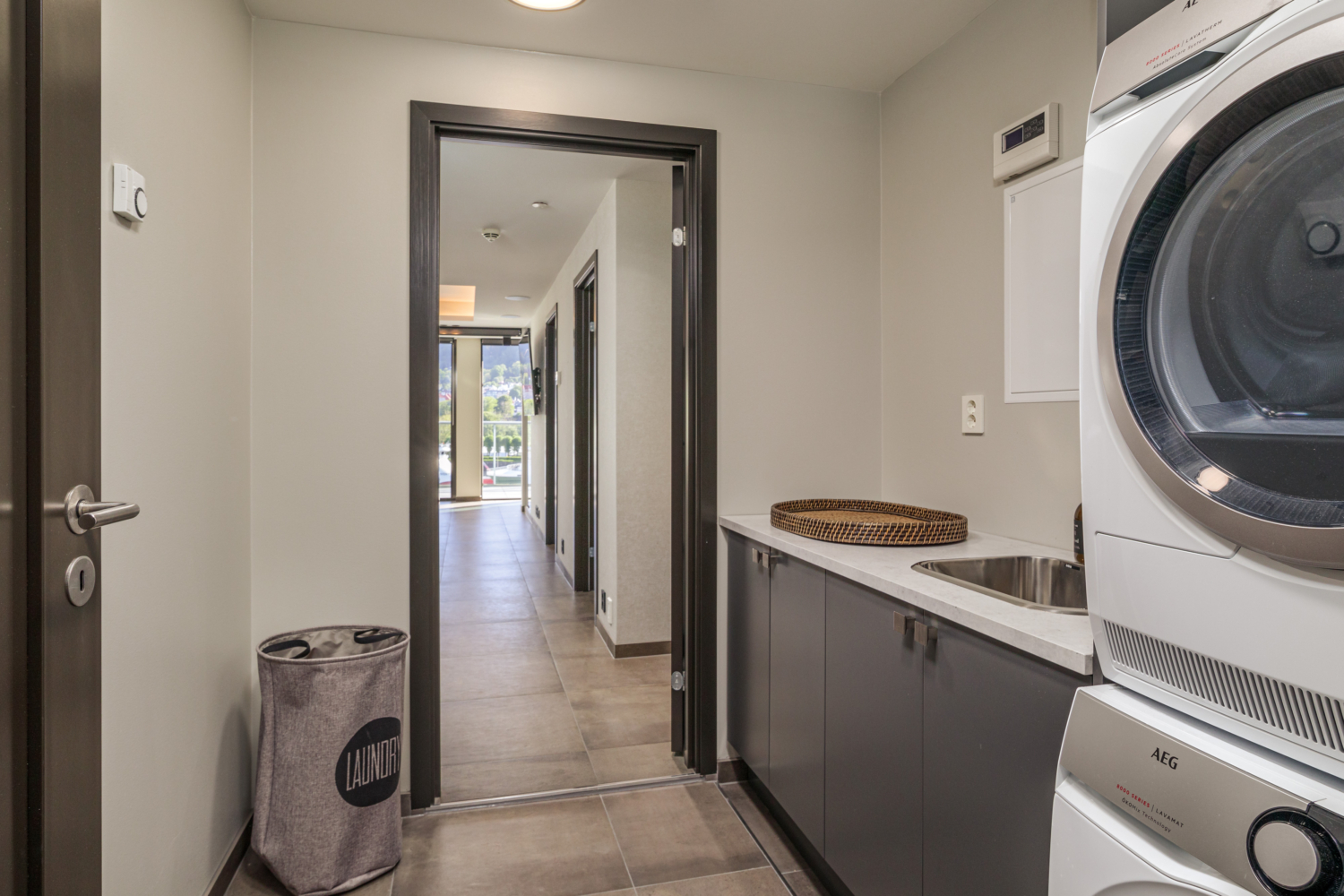 Bright laundry room with washer, dryer, and laundry basket inside a modern apartment.