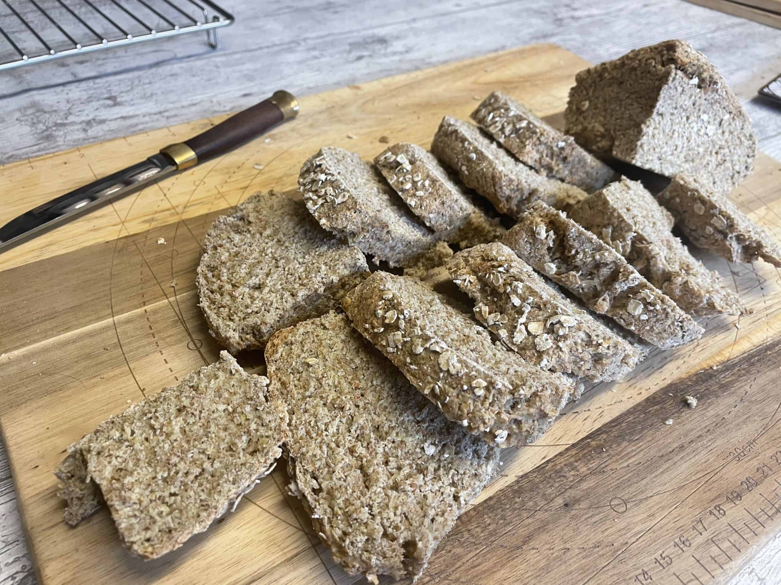 Irish Soda Bread sliced into pieces on a wooden chopping board, knife to side.