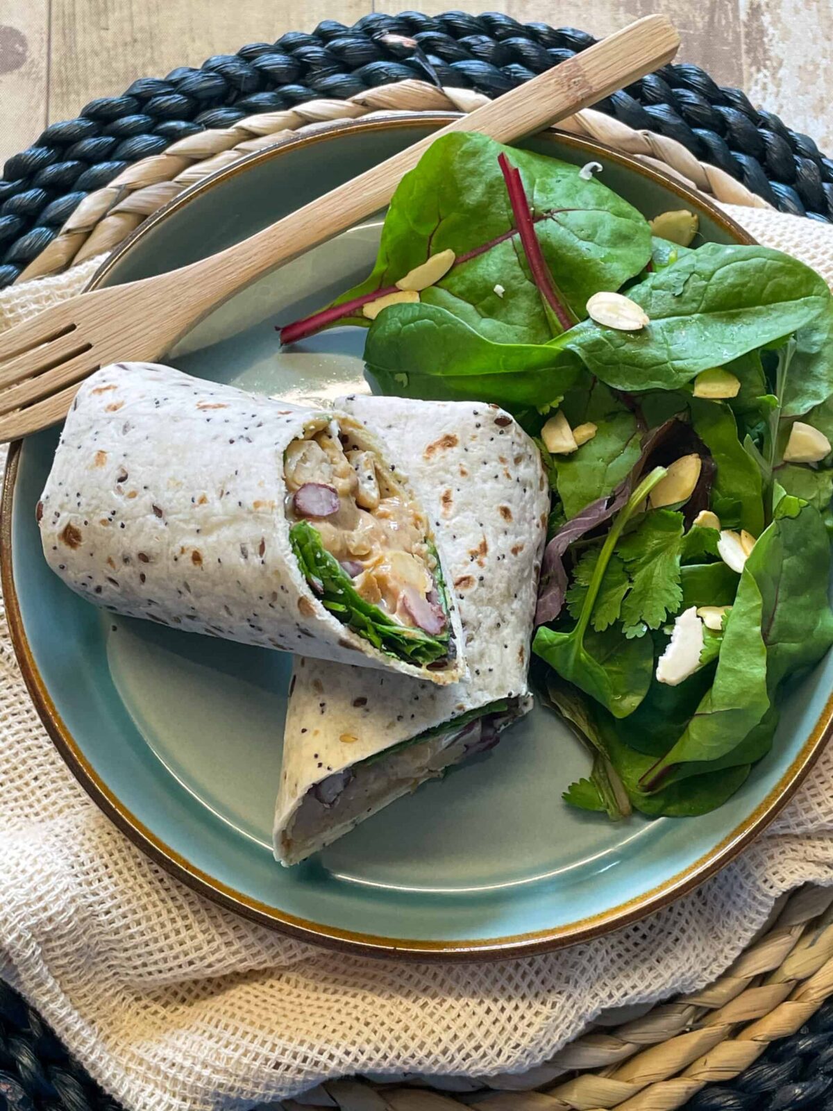 Vegan coronation chicken sandwich on a blue plate with a wicker mat background.
