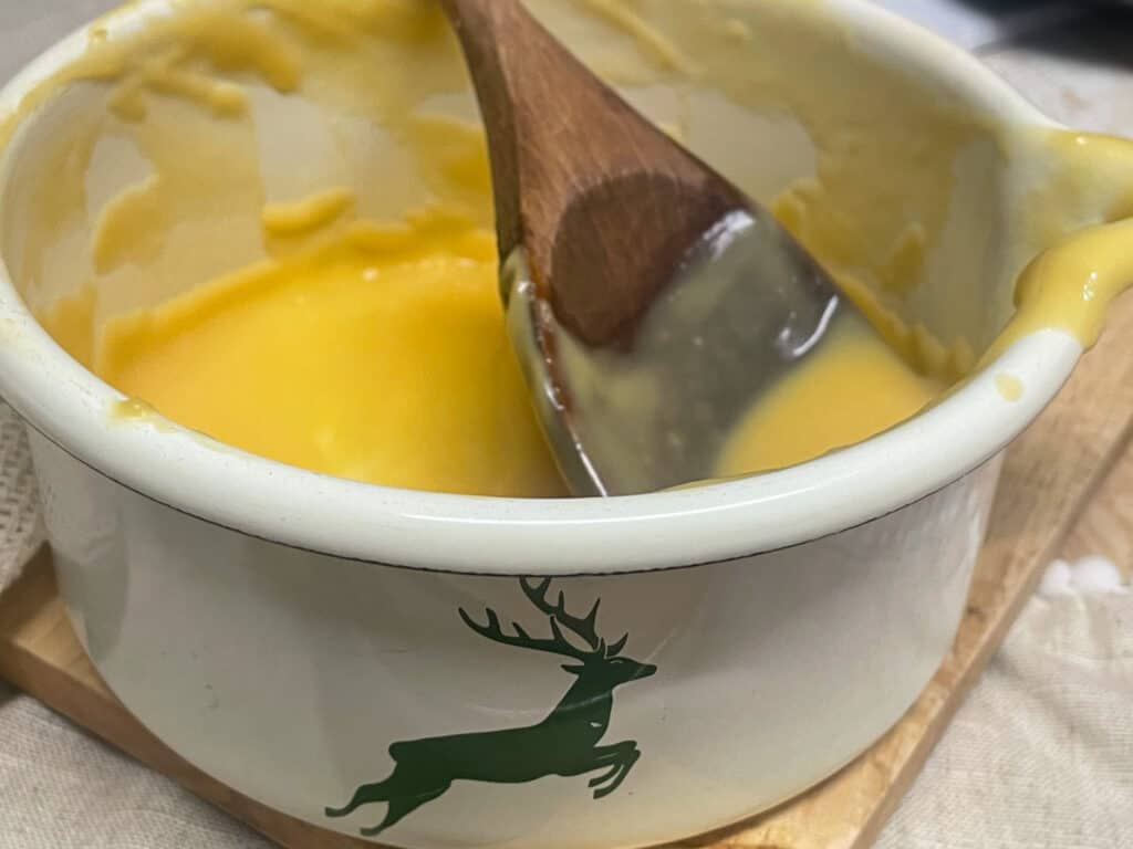 Custard in small pan with wooden spoon.