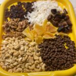 trail mix ingredients set out on yellow tray.