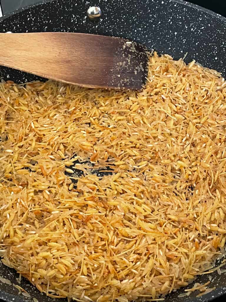 rice, vermicelli and orzo added to pan and browning in oil, wooden spatula to side.