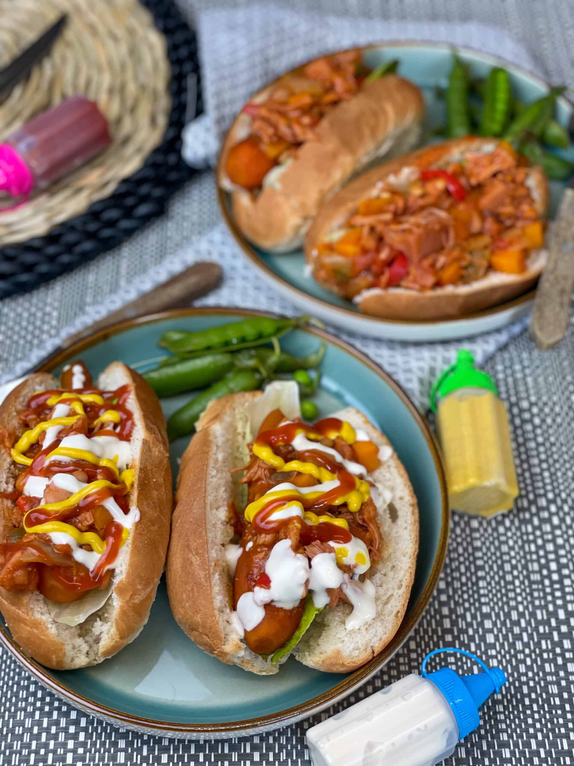 carrot hotdogs on blue plate, with peapods, mayo and mustard bottle on sides.