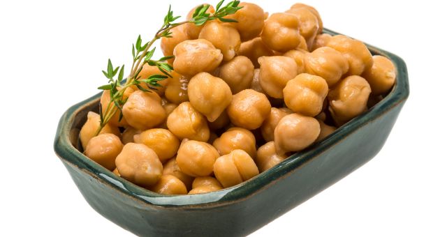 Image of chickpeas in small bowl with herb sprig.