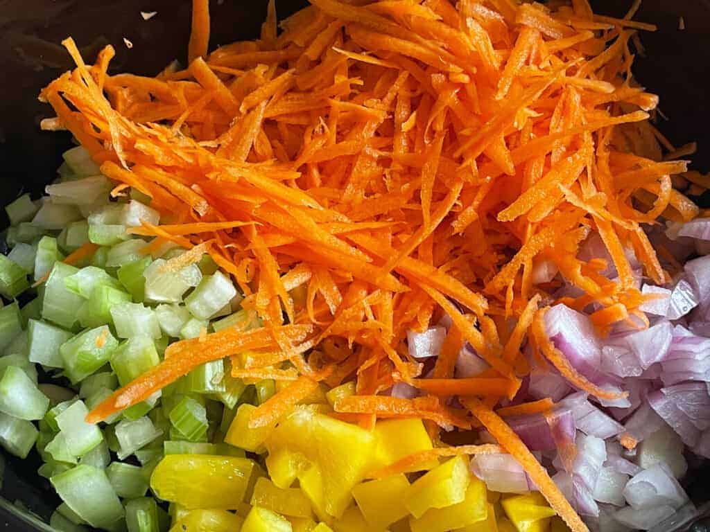 Grated carrot, diced celery, diced yellow pepper, diced onion added to slow cooker.