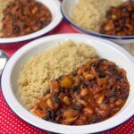 Three bowls of chilli sin carne with quinoa sitting on red check tea towel.