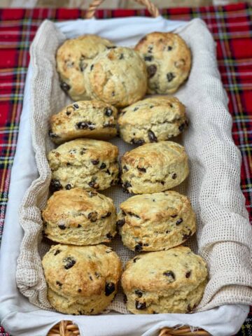 Fruit scones in long wicker basket, with white lining, tartan background.